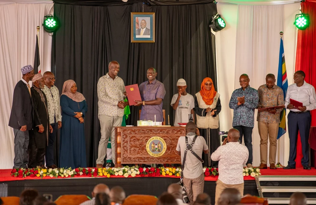 El presidente William Ruto, junto a integrantes de la comunidad pemba y funcionariado gubernamental, que dan fe de la firma del documento oficial que reconoce la ciudadanía keniana del pueblo pemba. © ACNUR/Charity Nzomo