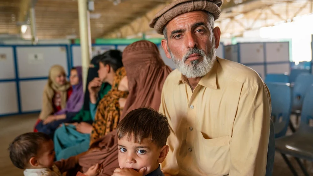 Ezatullah, de 45 años, sentado con su familia en instalaciones de ACNUR en Samarkhail, Afganistán, poco después de haber vuelto al país desde Pakistán.