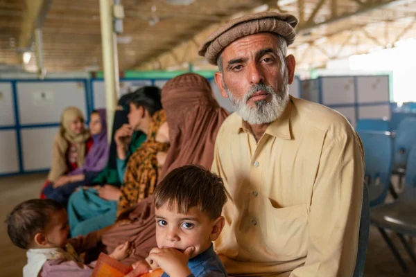 Ezatullah, de 45 años, sentado con su familia en instalaciones de ACNUR en Samarkhail, Afganistán, poco después de haber vuelto al país desde Pakistán.