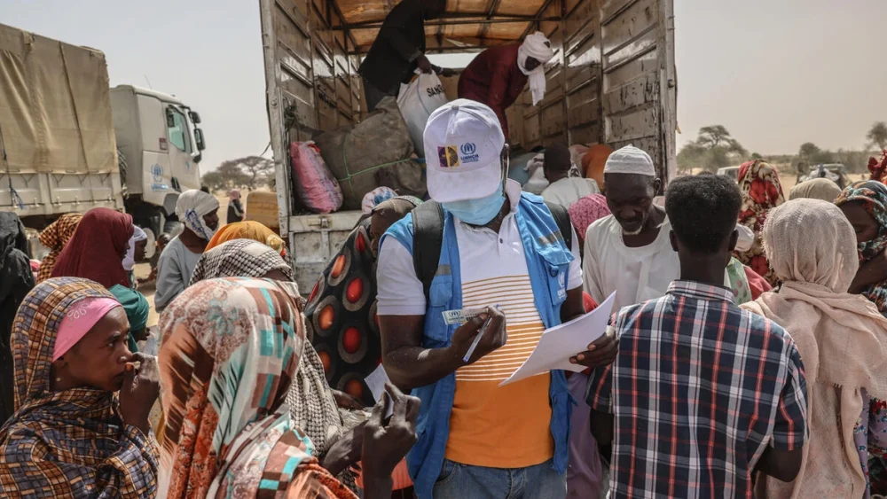 Un miembro del equipo de ACNUR revisa la documentación de las personas refugiadas recién llegadas de la región sudanesa de Darfur del Norte, en un centro de tránsito junto al cruce fronterizo de Tine, en Chad. © ACNUR/Caitlin Kelly