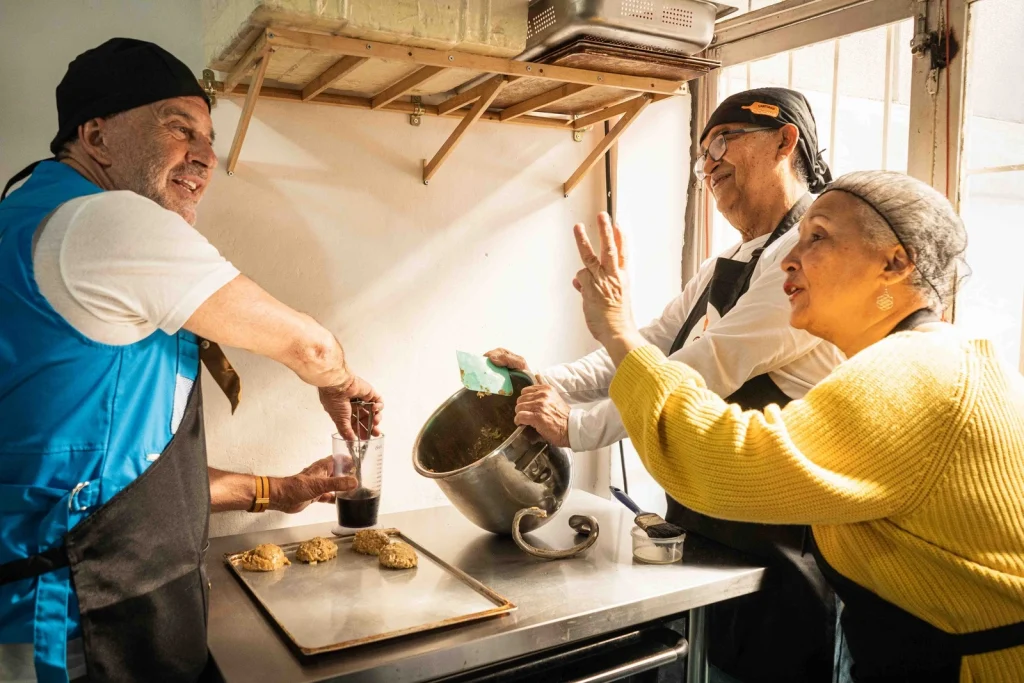 Víctor y María Teresa preparando sus productos junto al Embajador de Buena Voluntad de ACNUR, Osvaldo Laport. © ACNUR/Yhan Cancino