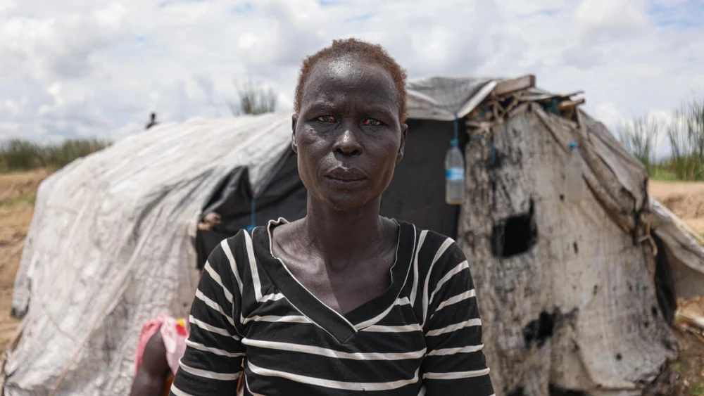 Aduot Wuoi Monjuon, desplazada interna, posa junto a su refugio en Bor, Sudán del Sur, donde se ha desplazado después de que las inundaciones la obligaran a huir de su aldea en el Estado de Jonglei, junto a su familia. © ACNUR/Tiksa Negeri