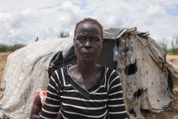 Aduot Wuoi Monjuon, desplazada interna, posa junto a su refugio en Bor, Sudán del Sur, donde se ha desplazado después de que las inundaciones la obligaran a huir de su aldea en el Estado de Jonglei, junto a su familia. © ACNUR/Tiksa Negeri